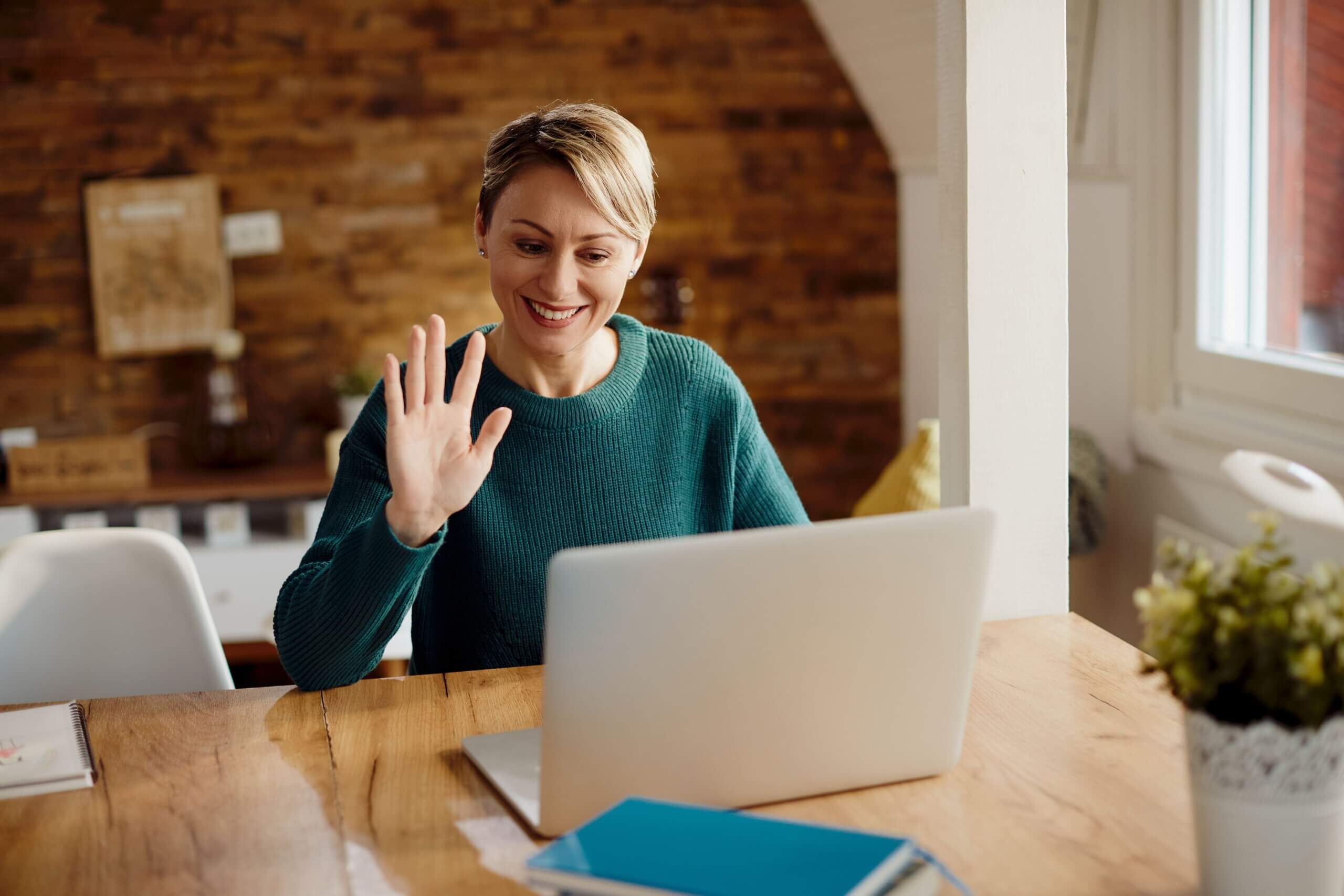 Как провести успешное удалённое собеседование | Фото happy woman greeting someone during video call at home 1 scaled